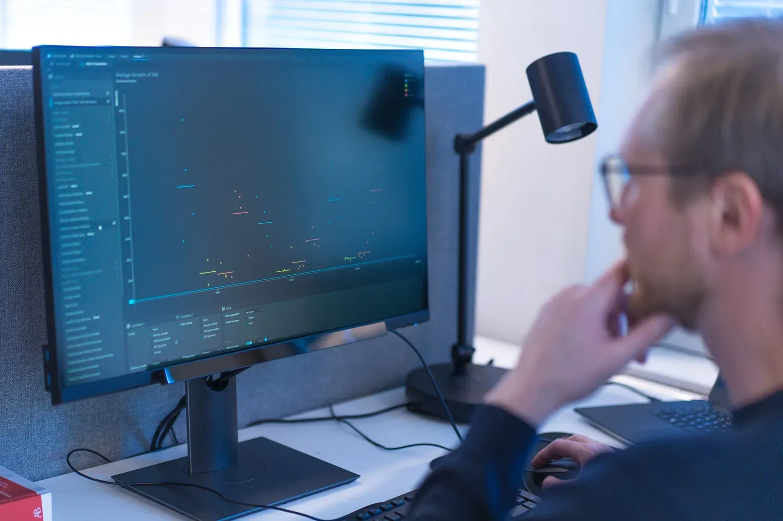 Badacz pracuje przy monitorze z otwartym oknem Tobii Pro Lab