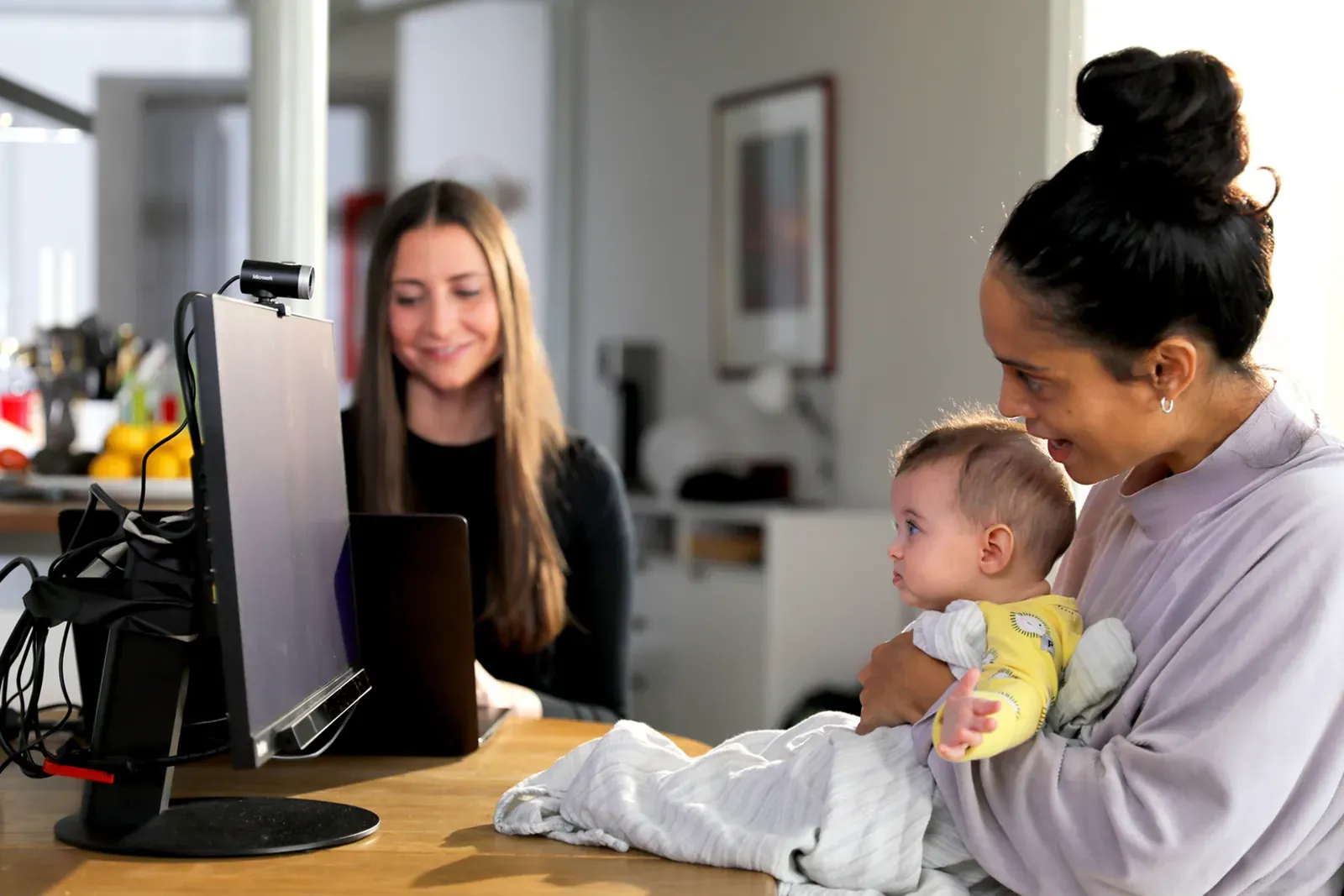 Niemowlę na kolanach mamy patrzy na monitor z eye trackerem; obok badaczka przy laptopie