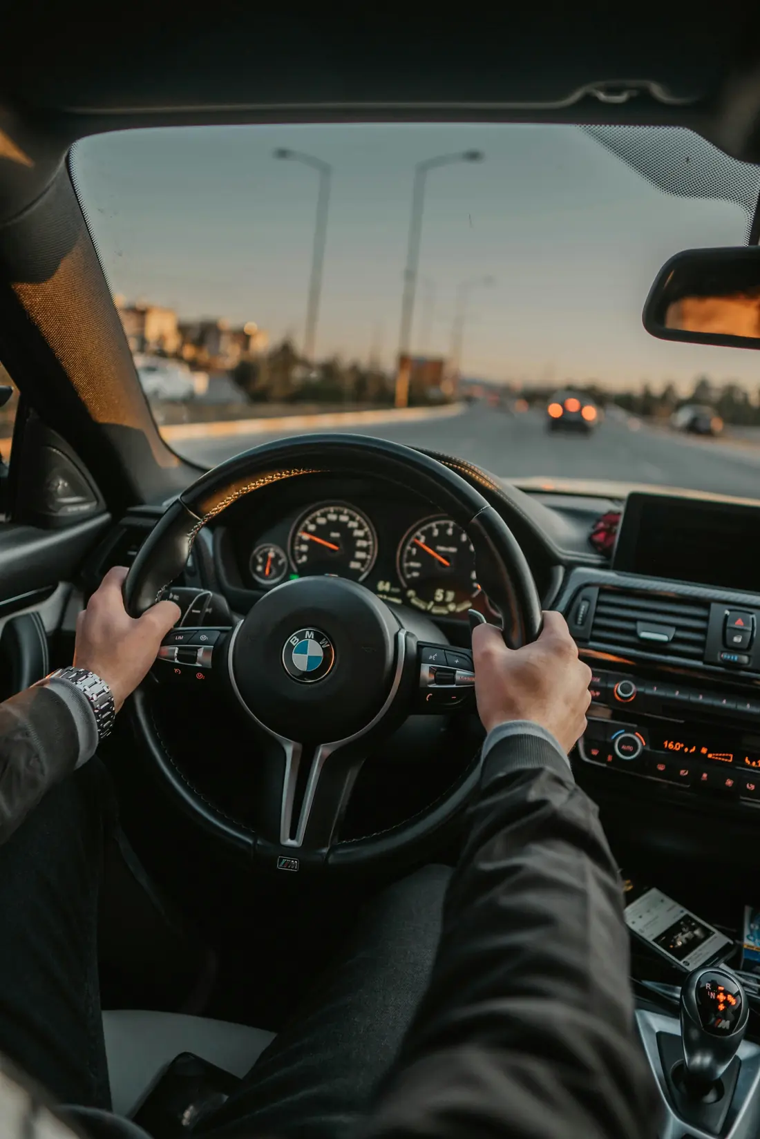 A driver’s hands on the steering wheel of a car while driving