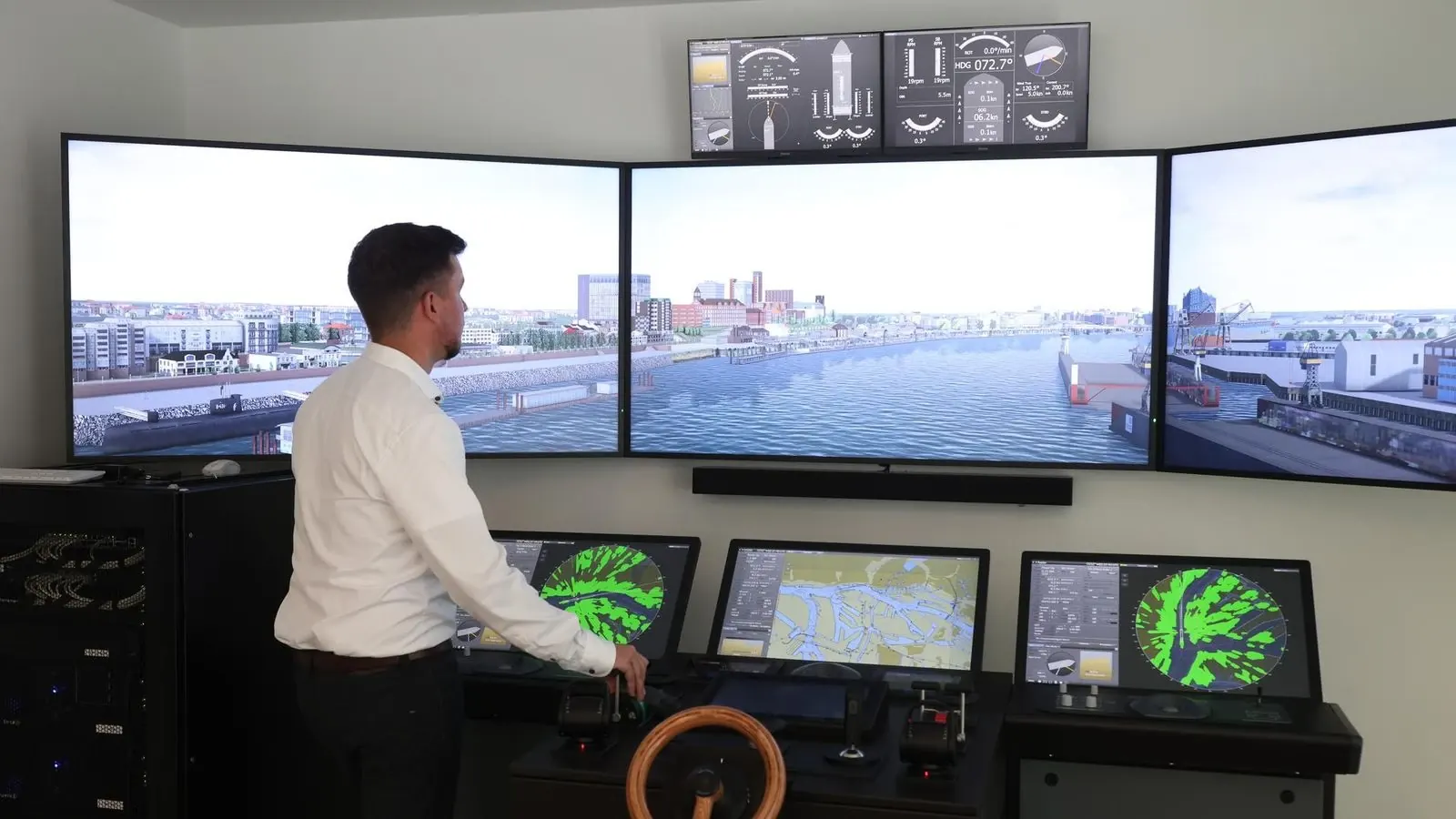 A ship’s bridge simulator: an officer at a console in front of panoramic screens showing a harbor