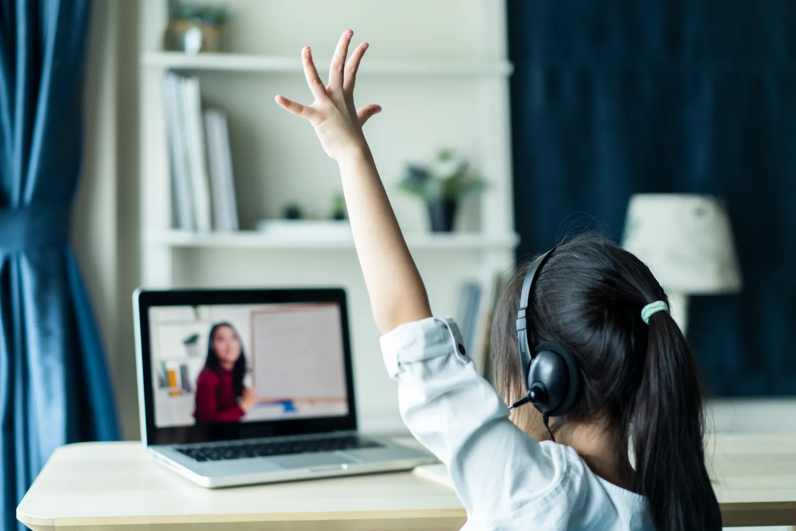 A child wearing headphones takes part in an online session on a laptop at home
